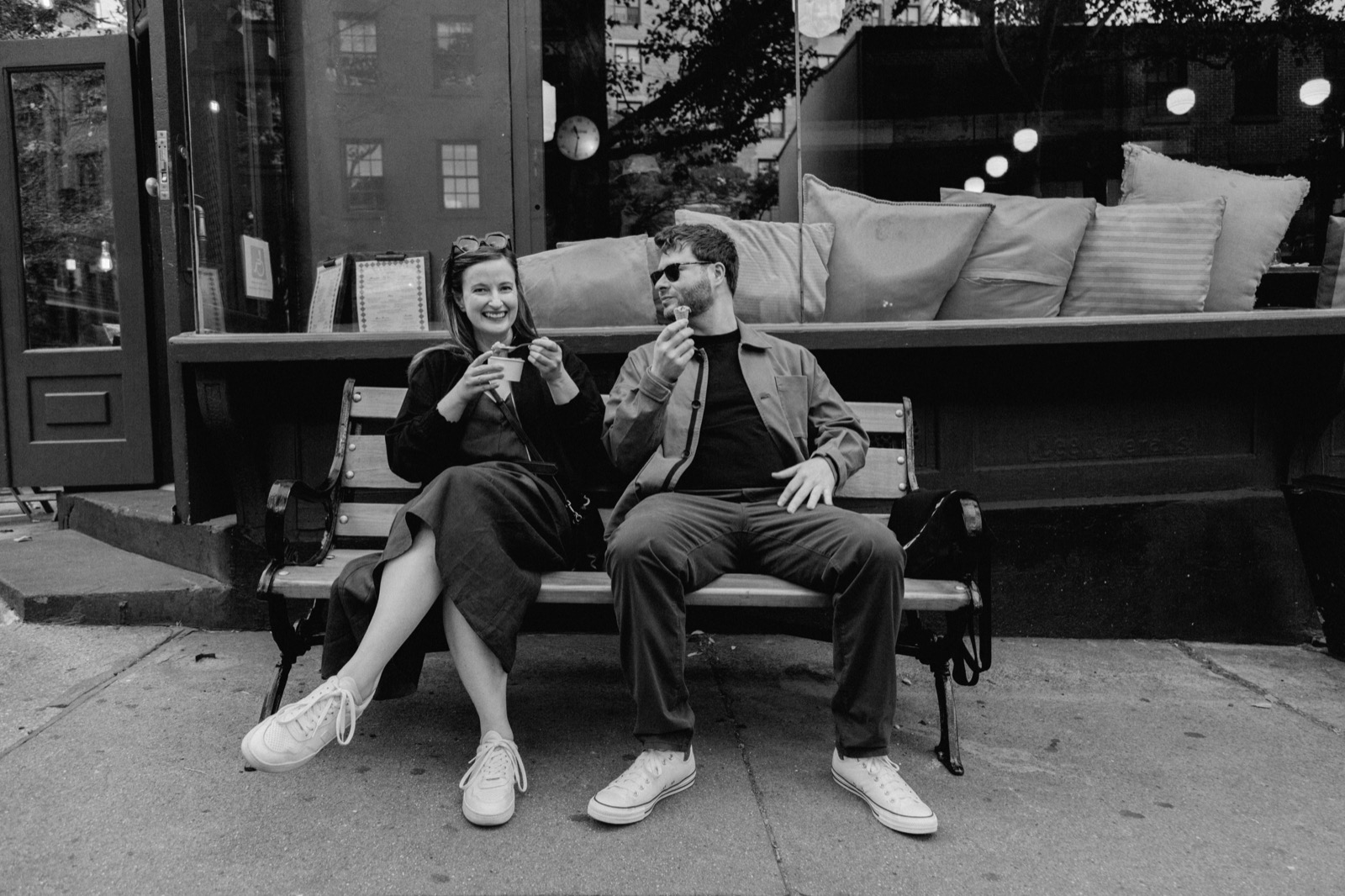 Heather and Kyle sharing ice cream on a bench outside a cafe, in black and white